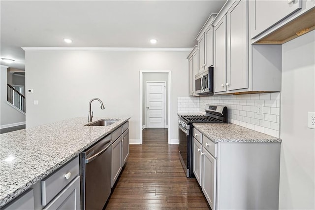 kitchen featuring dark wood-style flooring, a sink, appliances with stainless steel finishes, light stone countertops, and tasteful backsplash