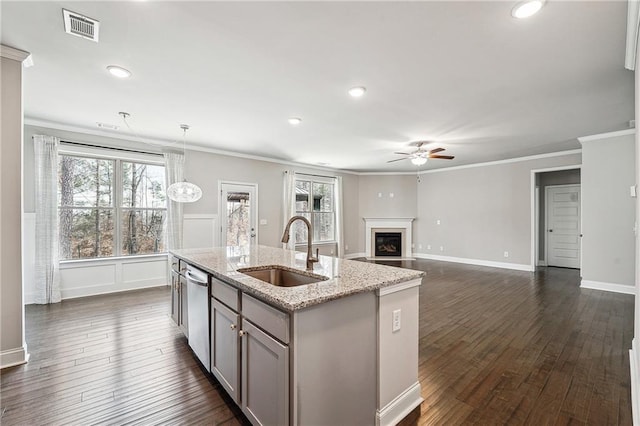 kitchen featuring dark wood-style floors, visible vents, a glass covered fireplace, a sink, and dishwasher