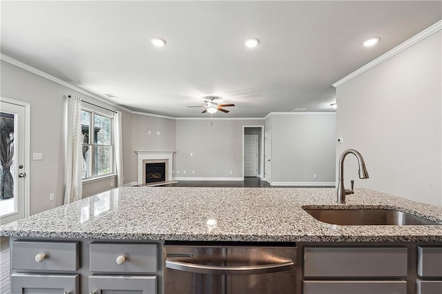 kitchen featuring light stone counters, a fireplace, a sink, gray cabinets, and dishwasher