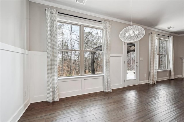 unfurnished dining area with visible vents, ornamental molding, hardwood / wood-style flooring, and a decorative wall