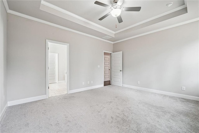 carpeted spare room featuring baseboards, a tray ceiling, and crown molding