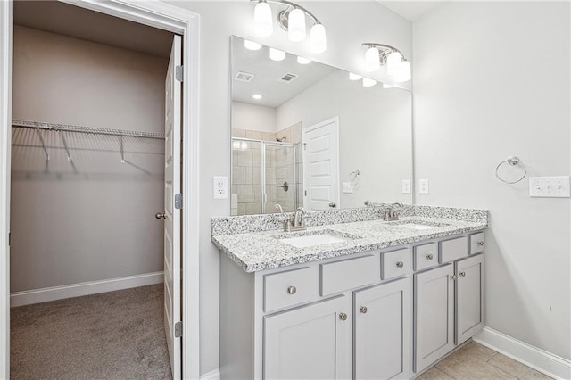 full bath featuring a stall shower, visible vents, a walk in closet, and a sink