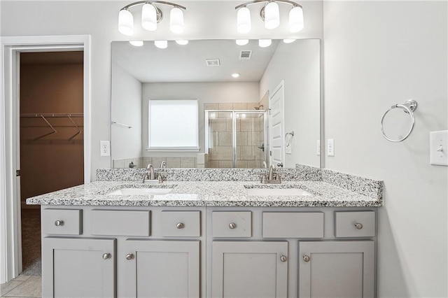 full bath featuring a spacious closet, double vanity, a sink, and a shower stall