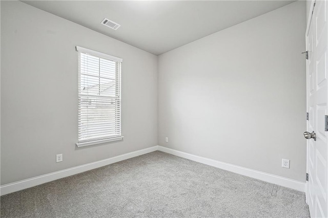 carpeted empty room with a healthy amount of sunlight, baseboards, and visible vents