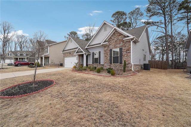 craftsman-style home with driveway, central AC unit, stone siding, fence, and a front yard