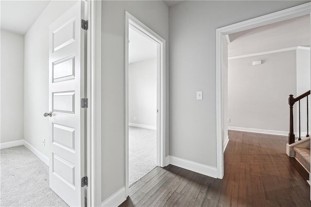 hall with carpet flooring, hardwood / wood-style floors, baseboards, and stairs