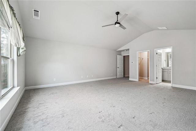 unfurnished bedroom featuring a walk in closet, lofted ceiling, light carpet, ceiling fan, and baseboards