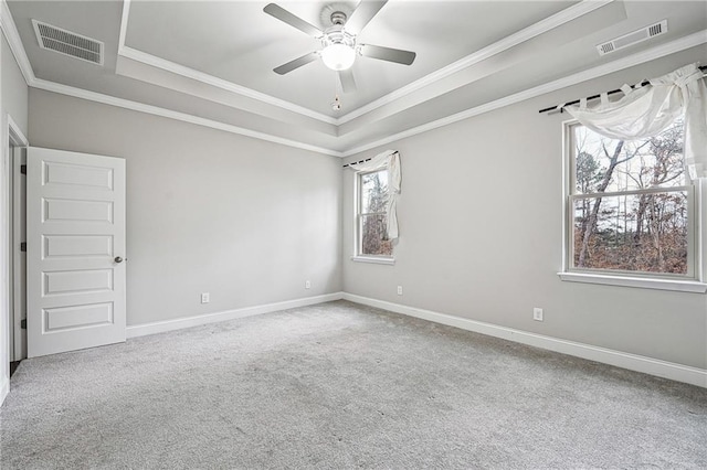 carpeted spare room featuring a tray ceiling, visible vents, and baseboards