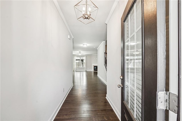 hall with dark wood-style floors, baseboards, a notable chandelier, and crown molding