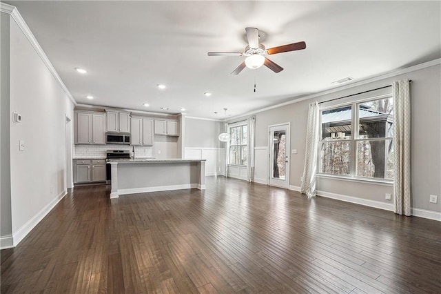 unfurnished living room featuring a wealth of natural light, dark wood-type flooring, and visible vents