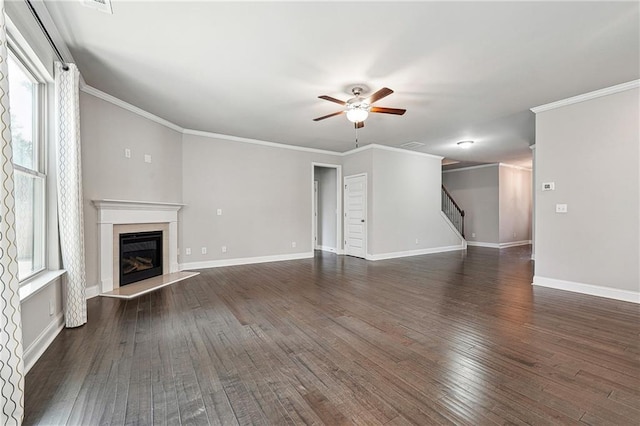 unfurnished living room with ceiling fan, dark wood-style flooring, a fireplace, baseboards, and crown molding