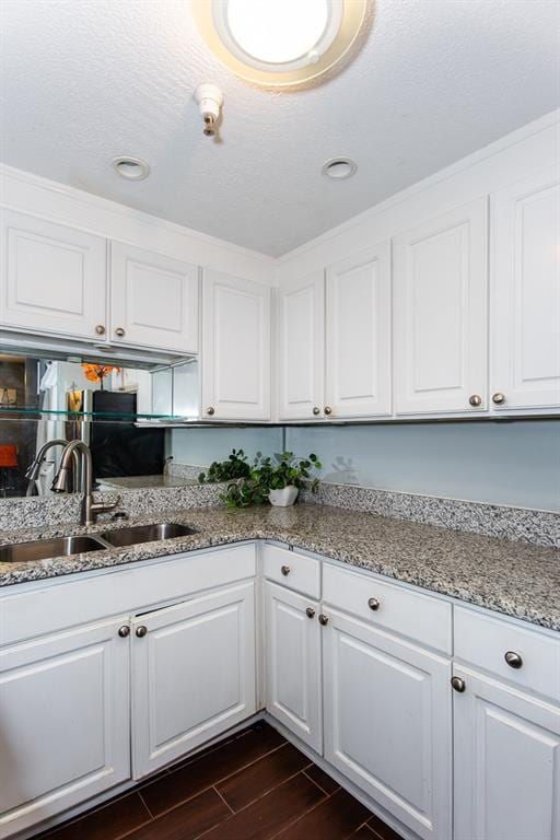 kitchen featuring a sink, white cabinetry, dark wood finished floors, light stone countertops, and recessed lighting