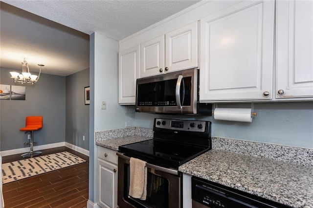 kitchen with stainless steel appliances, baseboards, white cabinetry, dark wood-style flooring, and a chandelier