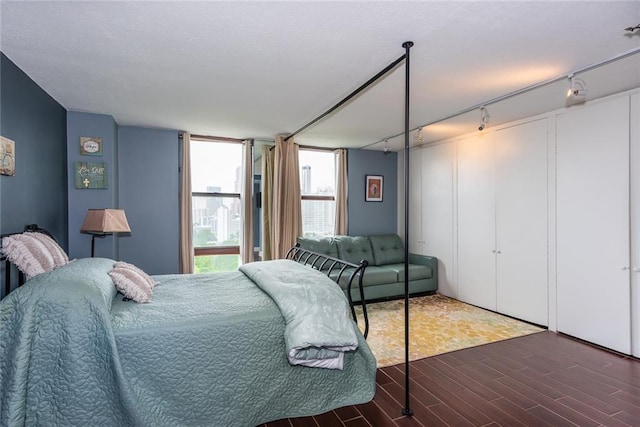 bedroom with rail lighting and wood finished floors