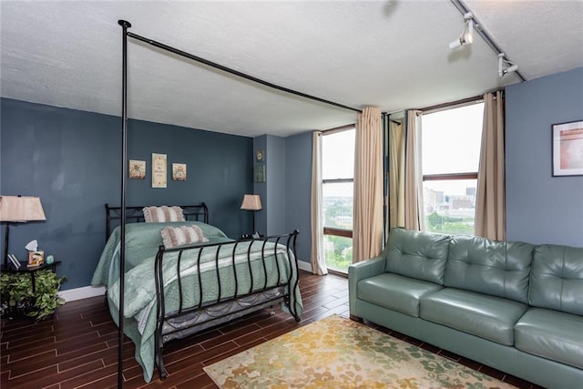 bedroom featuring a textured ceiling, wood tiled floors, and baseboards