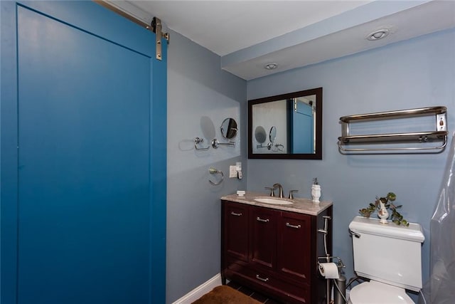 bathroom with baseboards, vanity, and toilet