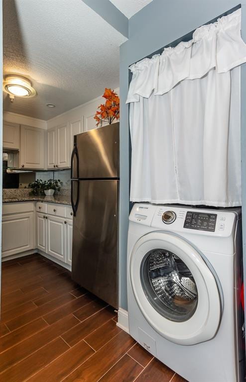 clothes washing area featuring washer / dryer, dark wood finished floors, and a textured ceiling