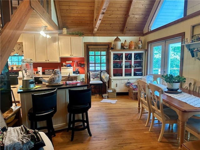 226 Hawk Hill Ln, Lakemont, GA 30552 - kitchen featuring wooden ceiling with exposed beams, light wood-style floors, white cabinets, dark countertops, and a kitchen bar