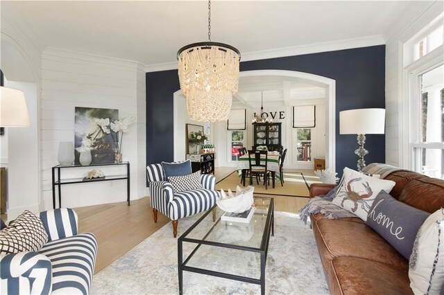 living area with a chandelier, ornamental molding, and wood finished floors