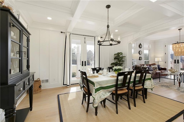 dining room featuring arched walkways, visible vents, a decorative wall, and beamed ceiling