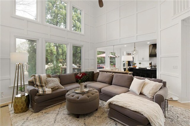 living area with a ceiling fan, a fireplace, light wood-style flooring, and a decorative wall