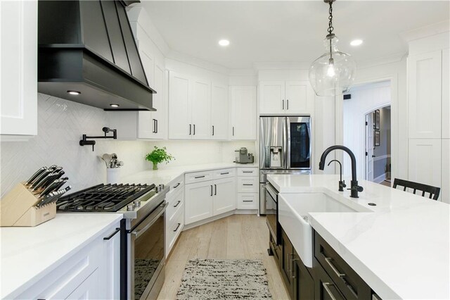 kitchen featuring custom exhaust hood, stainless steel appliances, light countertops, backsplash, and white cabinetry