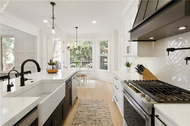 kitchen featuring ornamental molding, light countertops, appliances with stainless steel finishes, and range hood