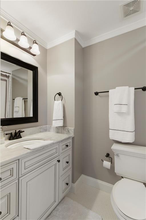 bathroom featuring baseboards, visible vents, toilet, and crown molding