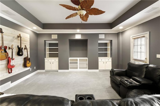 living area featuring built in shelves, a tray ceiling, and light colored carpet