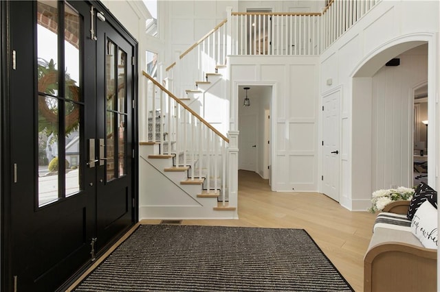 entryway with arched walkways, a healthy amount of sunlight, wood finished floors, and a decorative wall