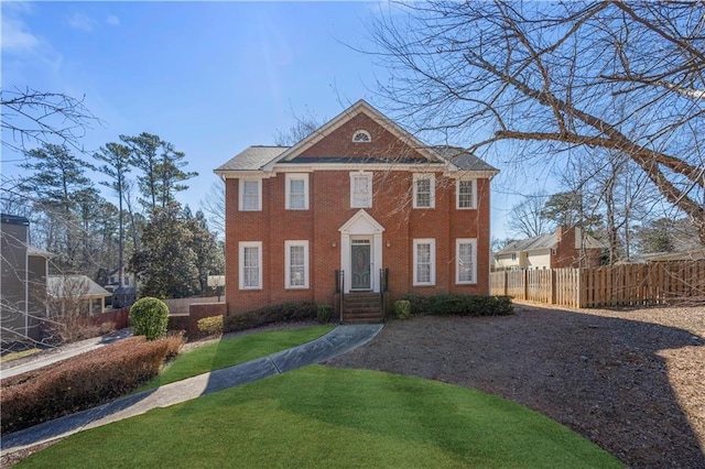 view of front of home featuring a front yard, fence, and brick siding