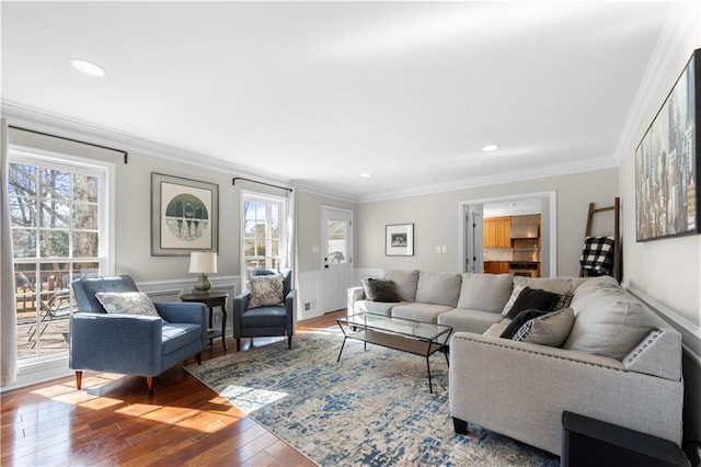 living area featuring hardwood / wood-style flooring, recessed lighting, crown molding, and wainscoting