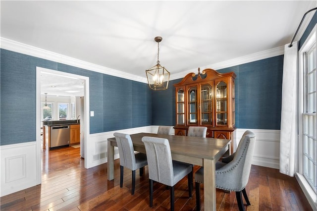 dining space featuring wallpapered walls, dark wood-type flooring, and wainscoting