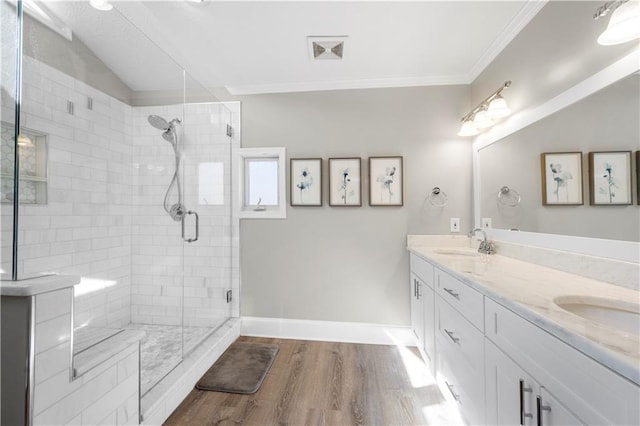 full bath with wood finished floors, a sink, baseboards, a stall shower, and crown molding