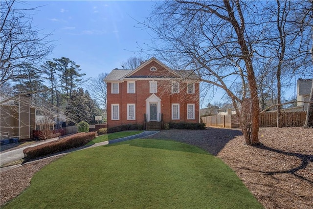 view of front of property featuring brick siding, a front yard, and fence