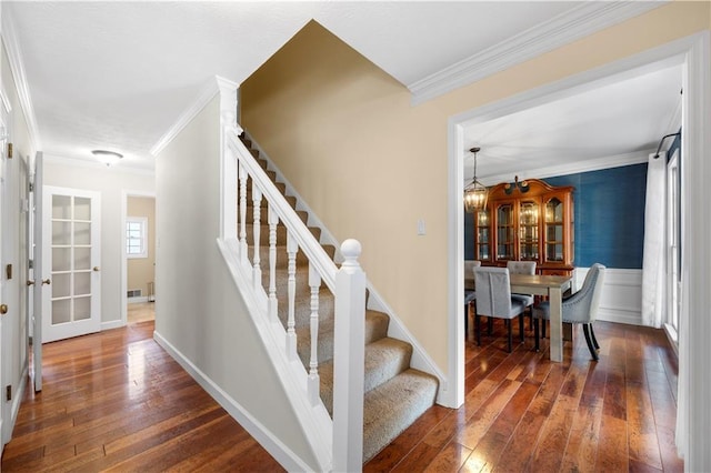 stairway with hardwood / wood-style flooring, baseboards, and crown molding