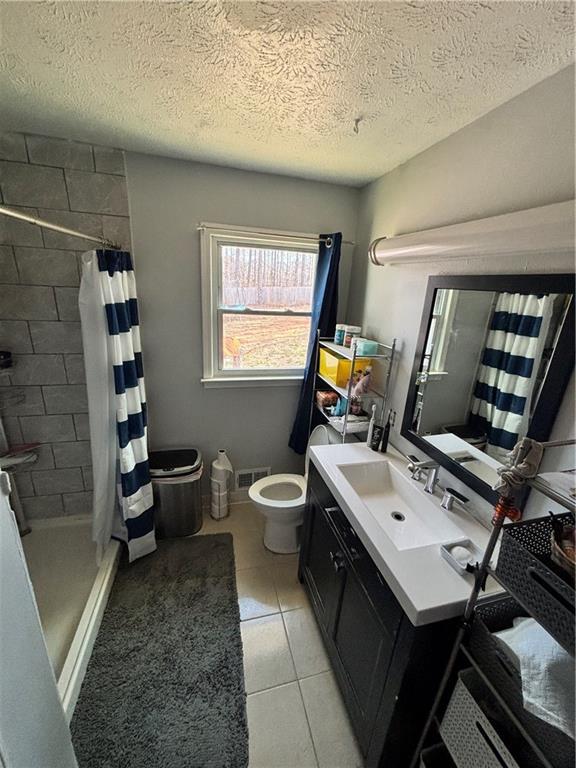 bathroom featuring toilet, vanity, visible vents, and a stall shower