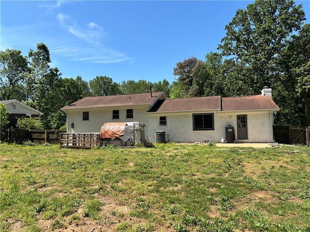 back of house featuring fence, a lawn, a chimney, and brick siding