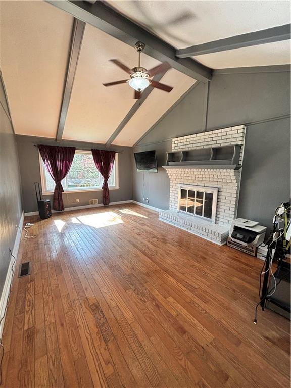 unfurnished living room featuring vaulted ceiling with beams, visible vents, ceiling fan, hardwood / wood-style floors, and a fireplace