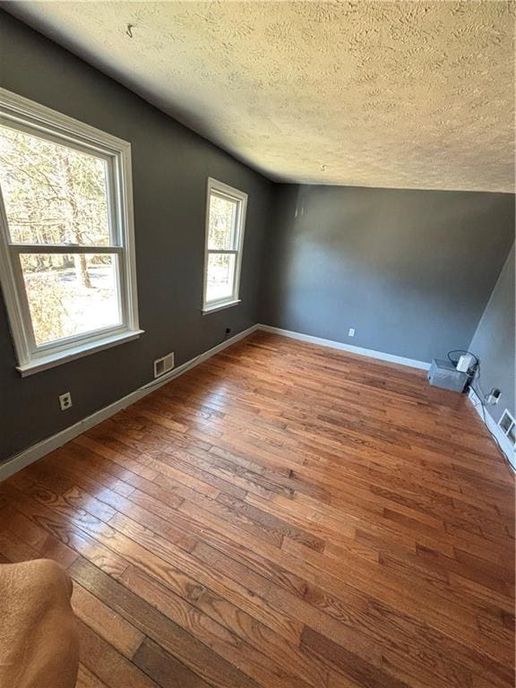 unfurnished room featuring hardwood / wood-style floors, plenty of natural light, baseboards, and a textured ceiling