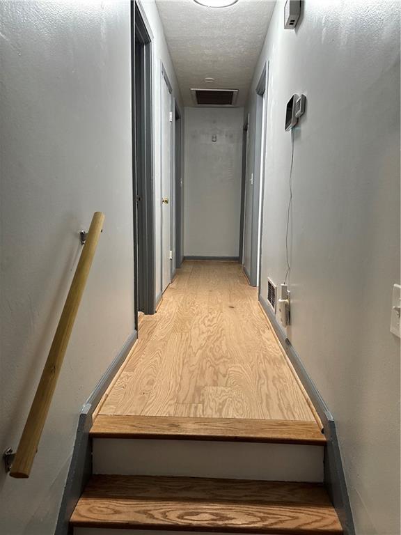 corridor featuring light wood-style flooring and a textured ceiling