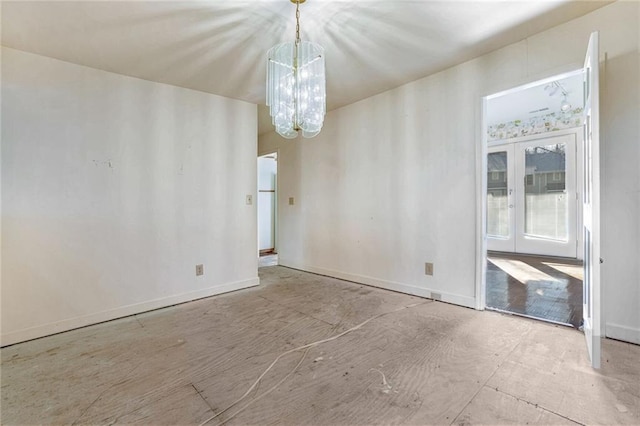 spare room with french doors and an inviting chandelier