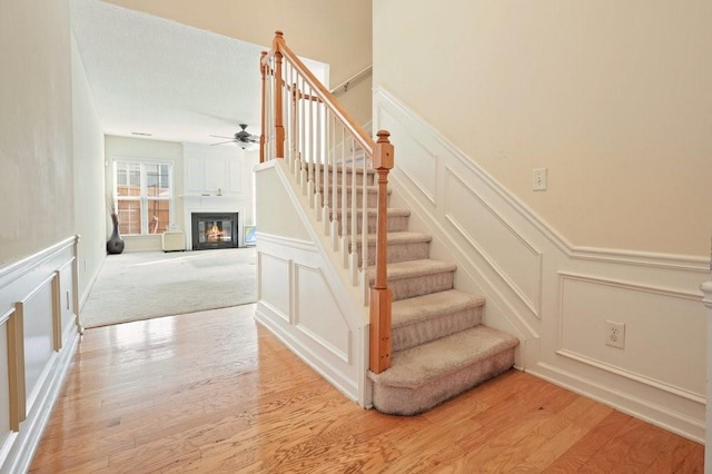 stairway with ceiling fan and wood-type flooring