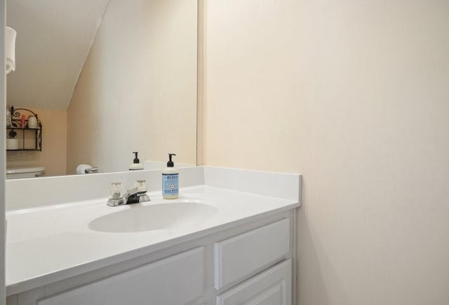 bathroom with vanity, vaulted ceiling, and toilet