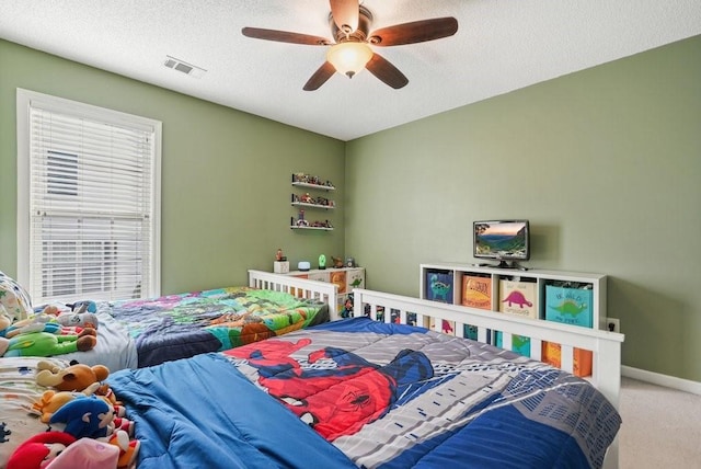 bedroom with ceiling fan, carpet, and a textured ceiling