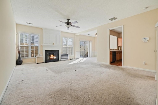 unfurnished living room with a textured ceiling, light colored carpet, and ceiling fan