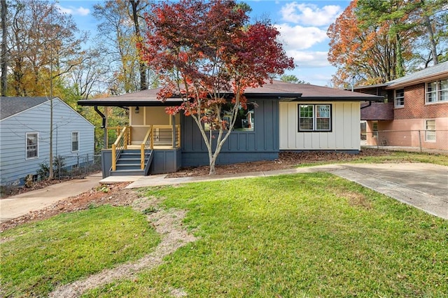 view of front of property featuring covered porch, a front lawn, board and batten siding, and fence