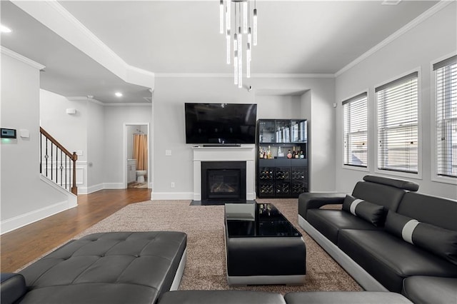 living room with ornamental molding, wood finished floors, stairway, a fireplace with flush hearth, and recessed lighting