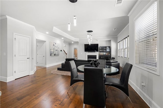 dining space with baseboards, crown molding, hardwood / wood-style flooring, a fireplace, and recessed lighting