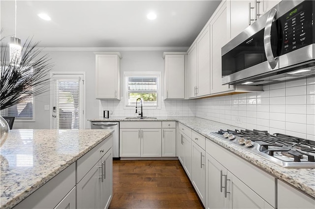 kitchen featuring appliances with stainless steel finishes, a sink, decorative backsplash, ornamental molding, and white cabinetry